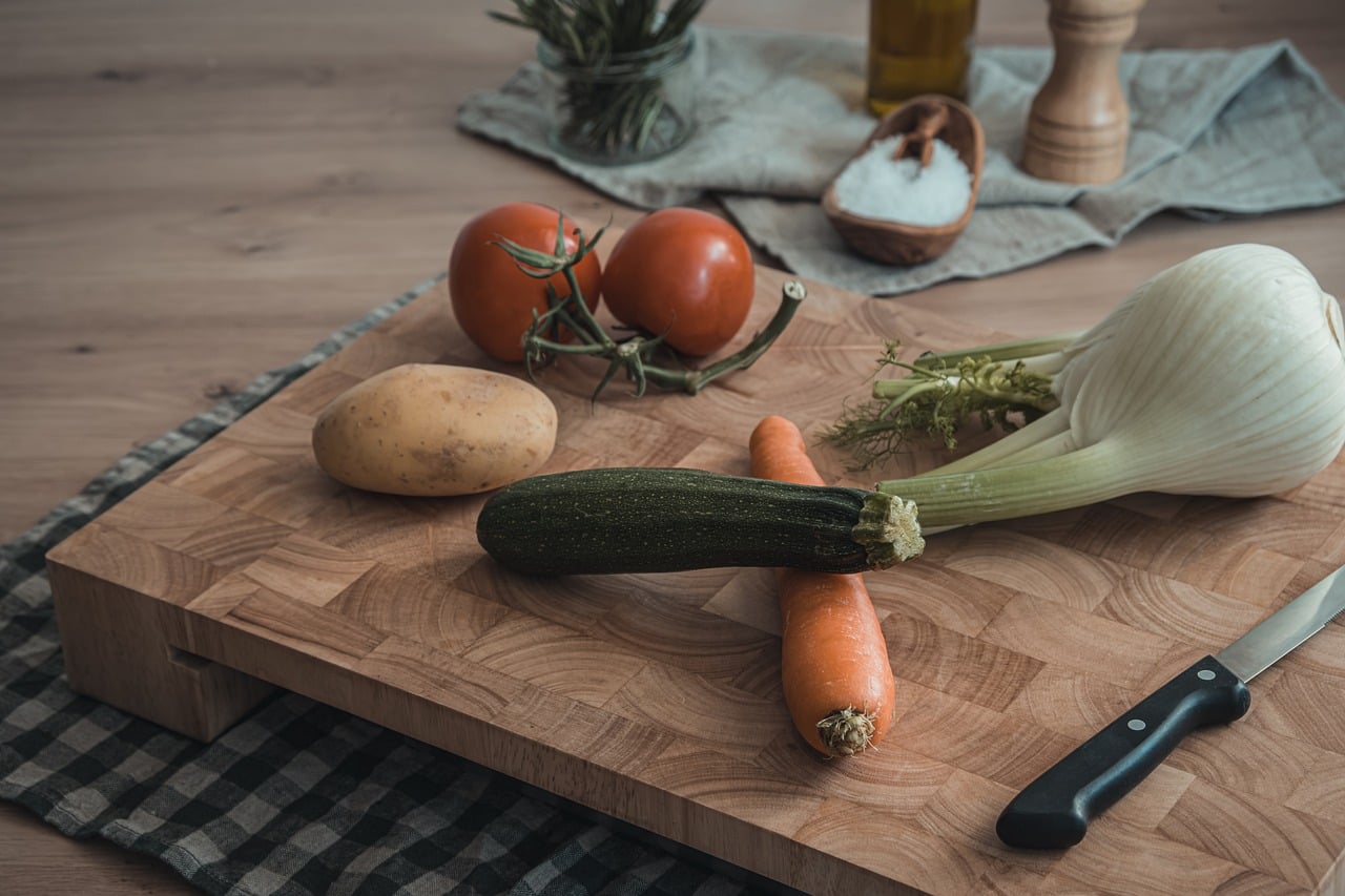 cooking, natural, wooden board, carrot, zucchini, potato, tomato, fennel, knife, olive oil, pepper, salt, herb, food preparation, table setting, kitchen utensil, home cooking, healthy eating, outdoor picnic, rustic kitchen